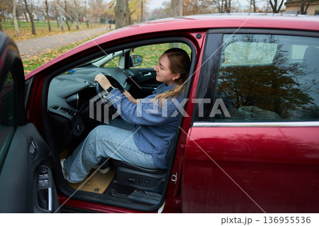 Woman sitting in car in autumn parking lot 136955536