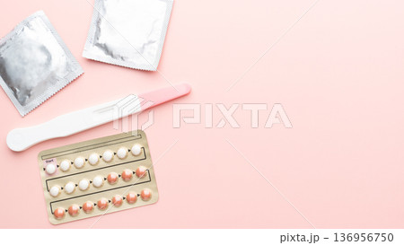 Pregnancy test with birth control pills and condoms on pink background. Contraception, family planning, sexual and reproductive health concept. 136956750