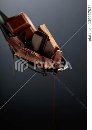 Melting pieces of bitter chocolate on a black background. 136957024