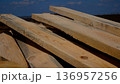 Wooden planks lie on the construction site against the background of a blue sky.  136957256