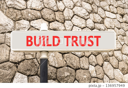 Build trust symbol. Concept words Build trust on beautiful big white road sign. Beautiful grey stone wall background. Business and build trust concept, copy space. 136957949