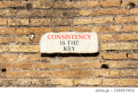 Consistency is the key symbol. Concept words Consistency is the key on beautiful white marble sign plate. Beautiful brick wall background. Business consistency is the key concept. Copy space. 136957952
