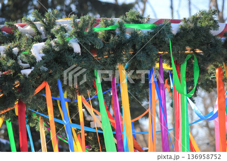 Spring festival arch made of evergreen branches decorated with many long colorful ribbons outdoors. Spring festival arch made of evergreen branches decorated with many long colorful ribbons outdoors. 136958752