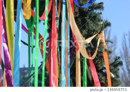 Spring festival arch made of evergreen branches decorated with many long colorful ribbons outdoors. Spring festival arch made of evergreen branches decorated with many long colorful ribbons outdoors. 136958753