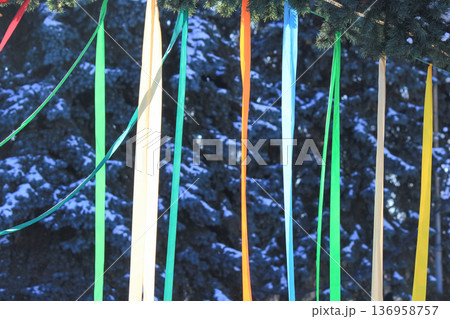Spring festival decorations with vibrant colorful ribbons on green pine branches against blue sky. Spring festival decorations with vibrant colorful ribbons on green pine branches against blue sky. 136958757