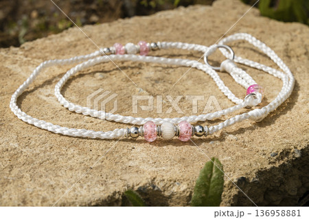 A professional handcrafted dog show lead lying on a natural stone background. This elegant white cord is decorated with beautiful pink and silver decorative beads for a stylish look in the ring 136958881