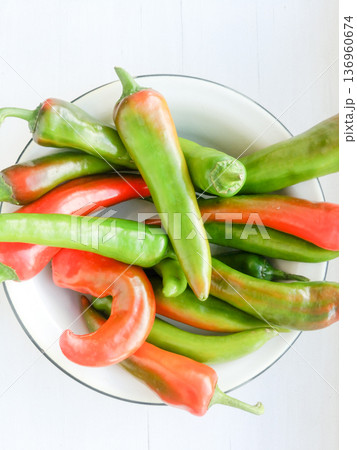 Red and green peppers in a metal plate. 136960674