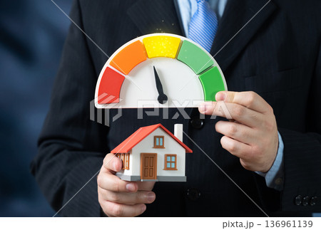 A house and an energy efficiency scale showing unsatisfactory values. Heat loss and excessive energy consumption. Home energy audit and renovation planning 136961139