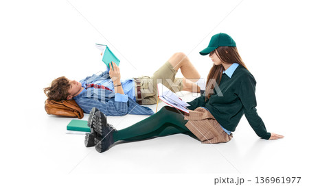 Young students reading books sitting on floor isolated on white. Young students reading books sitting on floor isolated on white. 136961977