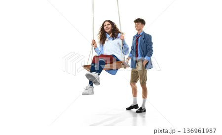 Teen girl swinging in preppy outfit with boy in blazer isolated on white 136961987