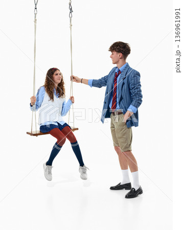 Teen girl on swing with stylish boy in preppy outfits isolated on white Teen girl on swing with stylish boy in preppy outfits isolated on white 136961991