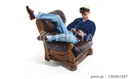 Teen boy in preppy outfit sitting in leather armchair with phone isolated on white Teen boy in preppy outfit sitting in leather armchair with phone isolated on white 136961997
