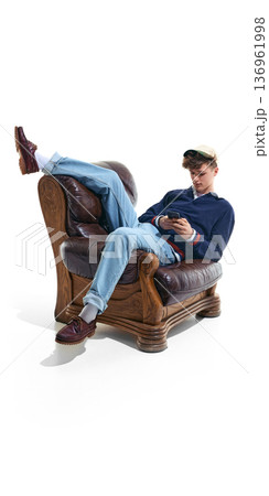 Teenage boy relaxing in armchair using smartphone isolated on white. Teenage boy relaxing in armchair using smartphone isolated on white. 136961998