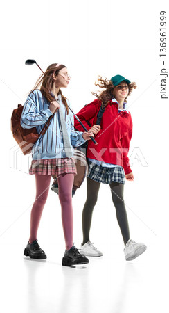 Teen girls in preppy style walking with golf equipment isolated on white. 136961999