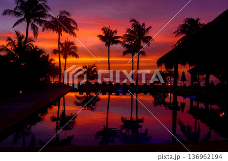Dramatic mexican sunset reflected in infinity pool with palms Dramatic mexican sunset reflected in infinity pool with palms 136962194