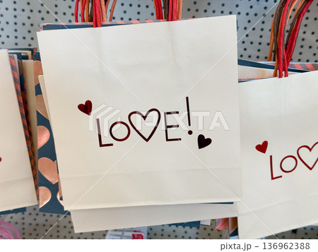Gift bags with love inscription and hearts. Romantic celebration, valentine shopping, packaging design, retail display concept Gift bags with love inscription and hearts. Romantic celebration, valentine shopping, packaging design, retail display concept 136962388