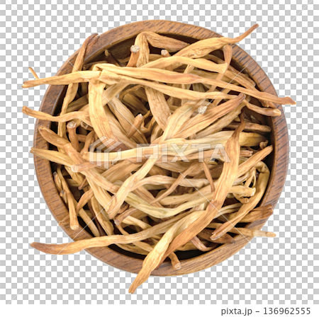 Top view of dried lily buds, also known as golden needles or huang hua cai, in a dark wooden bowl isolated. Traditional Chinese culinary ingredient for soups and stir-fry. Top view of dried lily buds, also known as golden needles or huang hua cai, in a dark wooden bowl isolated. Traditional Chinese culinary ingredient for soups and stir-fry. 136962555