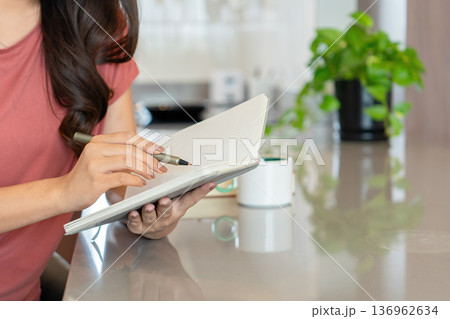 Smiling Asian Woman Writing in Notebook with Coffee Smiling Asian Woman Writing in Notebook with Coffee 136962634