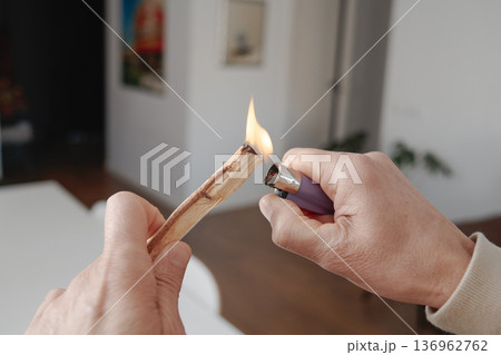 a man lights a sandalwood stick indoors 136962762