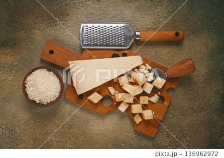 Freshly sliced and grated cheese, parmesan cheese, on a wooden chopping board, rustic style, no people Freshly sliced and grated cheese, parmesan cheese, on a wooden chopping board, rustic style, no people 136962972