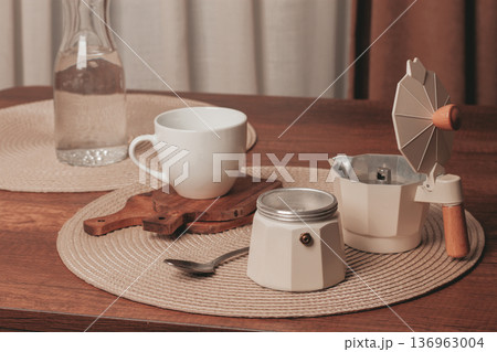 Coffee brewing setup on a rustic wooden table with a cup and water bottle in the morning light Coffee brewing setup on a rustic wooden table with a cup and water bottle in the morning light 136963004