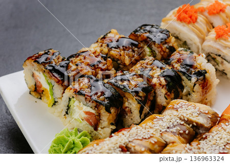 Sushi rolls with eel sauce sesame and seafood served on white plate closeup 136963324