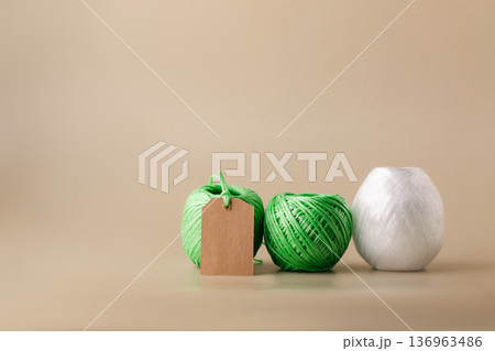 Various green and white spools of recycled polyester fiber with a blank label indicating the product's eco-friendliness. Recycling, conscious waste management 136963486