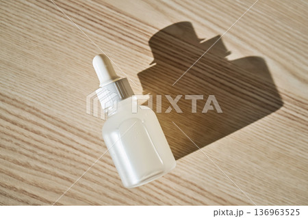 Dropper bottle with serum casting shadow on wood 136963525