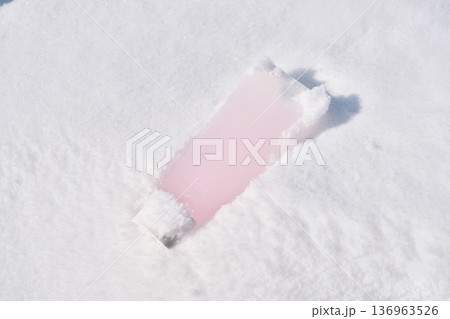 Pink cosmetic tube laying in fresh snow 136963526