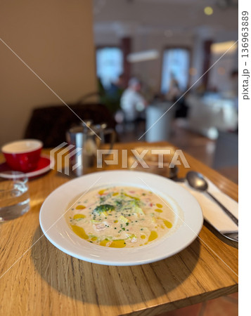 Creamy vegetable fish soup with broccoli and herbs on table. Homemade cuisine, healthy nutrition and cozy lunch concept. Creamy vegetable fish soup with broccoli and herbs on table. Homemade cuisine, healthy nutrition and cozy lunch concept. 136963889