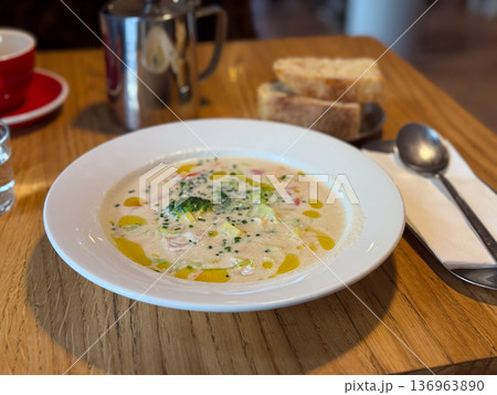 Close-up creamy vegetable fish soup with broccoli and herbs on table. Homemade cuisine, healthy nutrition and cozy lunch concept. 136963890