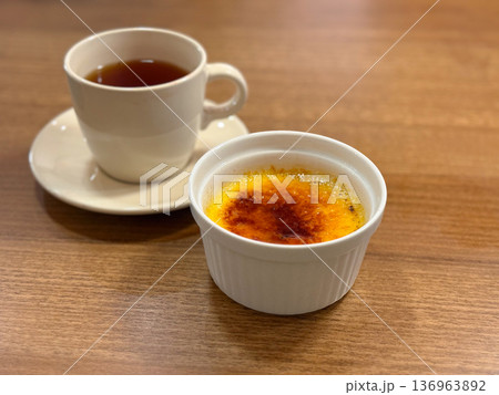 Creme brulee with caramel crust and cup of tea. French dessert, sweet indulgence and cafe lifestyle concept. Creme brulee with caramel crust and cup of tea. French dessert, sweet indulgence and cafe lifestyle concept. 136963892
