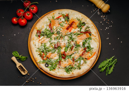 Gourmet pizza with salmon arugula cheese and sun dried tomatoes on wooden board 136963916