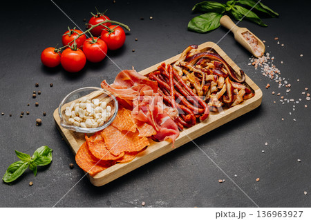 Assorted cured meats and snacks served on wooden board gourmet appetizer platter 136963927