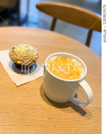 Coffee latte mug and muffin on wooden table in cafe close-up. Snack break, bakery dessert, cozy atmosphere, lifestyle moment 136963976