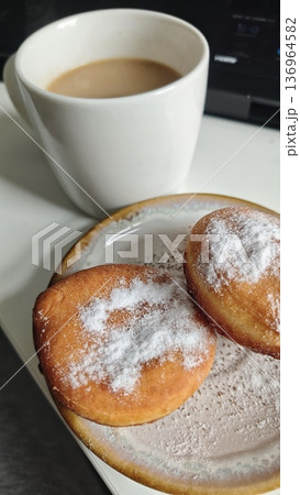Sweet donut with powdered sugar on ceramic plate served with cup of coffee. Cozy breakfast concept of dessert indulgence comfort food and morning routine Sweet donut with powdered sugar on ceramic plate served with cup of coffee. Cozy breakfast concept of dessert indulgence comfort food and morning routine 136964582