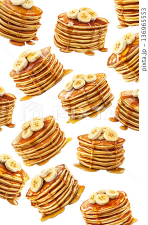 Stacks of banana topped pancakes drizzled with syrup from above plates, on white background, concept of breakfast 136965553