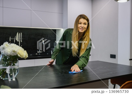 Woman wiping dust from kitchen island countertop 136965730