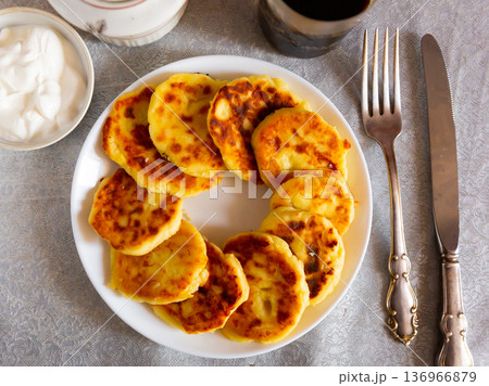 Russian syrniki, cheese pancakes with sour cream 136966879