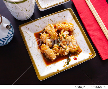 Squid in spicy sauce served on a white plate with onions 136966893