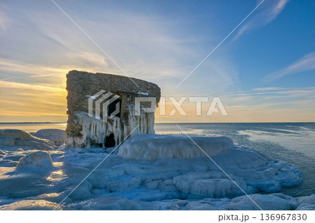 Icy Fortification Ruins at Sunset, thick ice formations on the Baltic Sea Coast in Liepaja 136967830