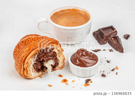 Chocolate filled croissant with coffee and cocoa spread on light background Chocolate filled croissant with coffee and cocoa spread on light background 136968835