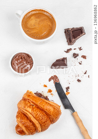 Chocolate croissant with coffee cup and cocoa spread on white background 136968862