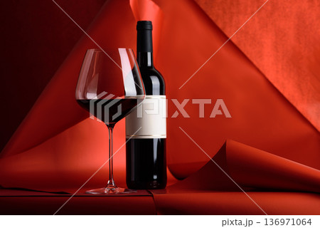 Red Wine Bottle and Glass on Red Background. Elegant Festive Still Life 136971064