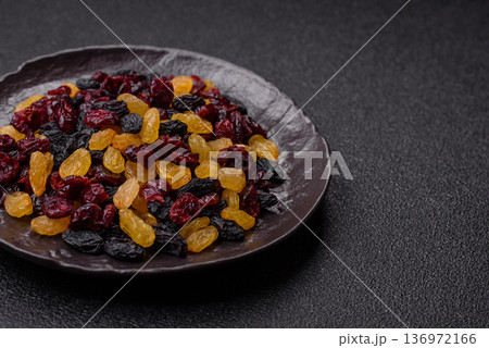 Dried cranberries, yellow and black sweet raisins as ingredients for a breakfast. Raisins and cranberries Dried cranberries, yellow and black sweet raisins as ingredients for a breakfast. Raisins and cranberries 136972166