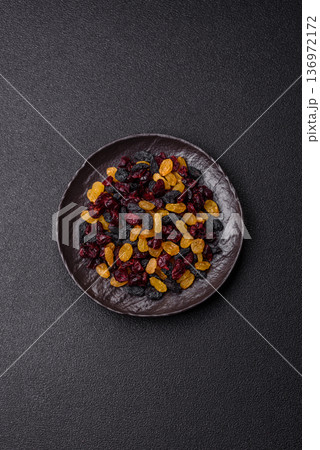 Dried cranberries, yellow and black sweet raisins as ingredients for a breakfast. Raisins and cranberries Dried cranberries, yellow and black sweet raisins as ingredients for a breakfast. Raisins and cranberries 136972172