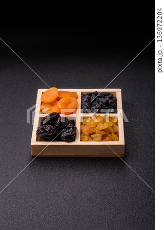 A variety of dried fruits, apricots, prunes, cranberries, raisins, figs, and dates for a healthy breakfast. A dried fruit mix 136972204