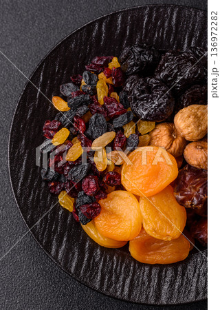 A variety of dried fruits, apricots, prunes, cranberries, raisins, figs, and dates for a healthy breakfast. A dried fruit mix 136972282
