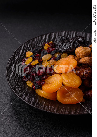 A variety of dried fruits, apricots, prunes, cranberries, raisins, figs, and dates for a healthy breakfast. A dried fruit mix 136972283