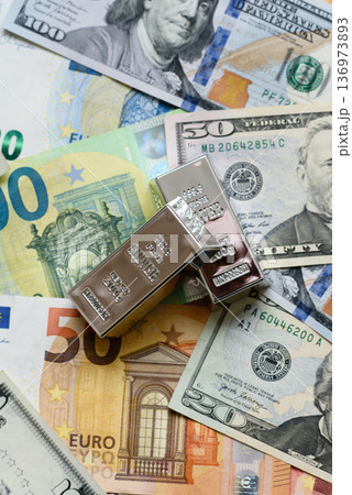 A silver bar, white metal against a backdrop of money, as a concept for the sales. A silver bar A silver bar, white metal against a backdrop of money, as a concept for the sales. A silver bar 136973893